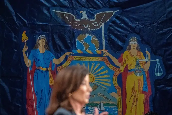 A profile of Gov. Kathy Hochul against of backdrop of the New York state seal